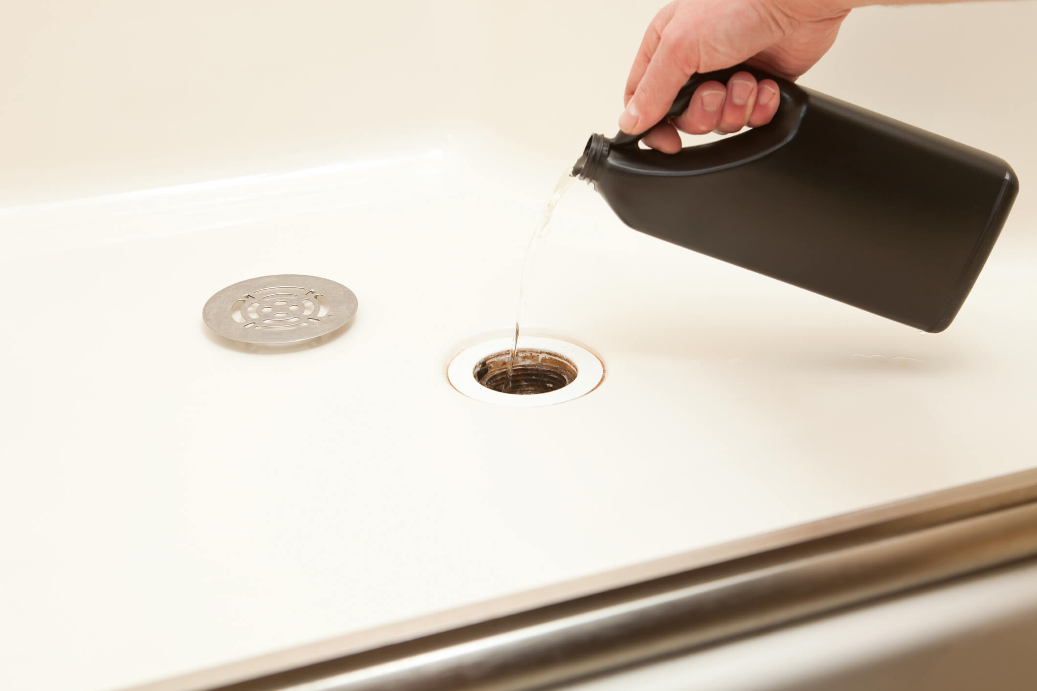 man pouring liquid drain cleaner down shower drain